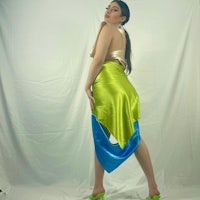a woman is posing in a green and blue skirt