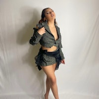 a woman posing in a black tweed jacket and shorts