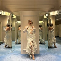 a woman in a white dress standing in front of mirrors