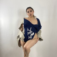 a woman in a blue bodysuit posing on a white background