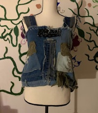 a mannequin wearing a denim vest with patches on it