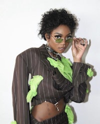 a woman wearing a brown suit and green sunglasses