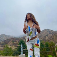 a woman in a colorful outfit posing on the side of a road