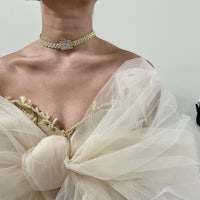 a woman wearing a gold choker and tulle dress