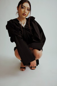 a woman crouching down in a black dress