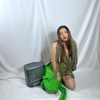 a woman in a green dress posing next to a tv