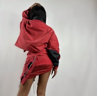 a woman is posing in a red jacket and skirt