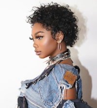 a black woman wearing a denim jacket and chains