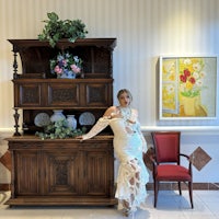 a woman in a white dress standing next to a dresser