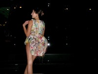 a woman in a dress standing in front of a car