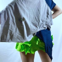 a woman wearing a grey t - shirt and green skirt