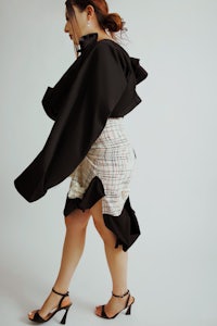 a woman wearing a black skirt and a black cape