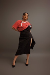a woman posing in a black skirt and red shirt