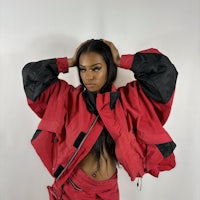 a woman wearing a red jacket and black pants