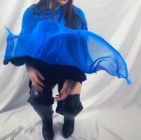 a woman in thigh high boots is wearing a blue cape