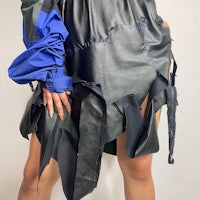 a woman wearing a black leather skirt with blue sleeves