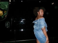 a woman in a denim dress standing in front of a van