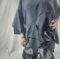 a woman wearing a denim poncho and silver pants